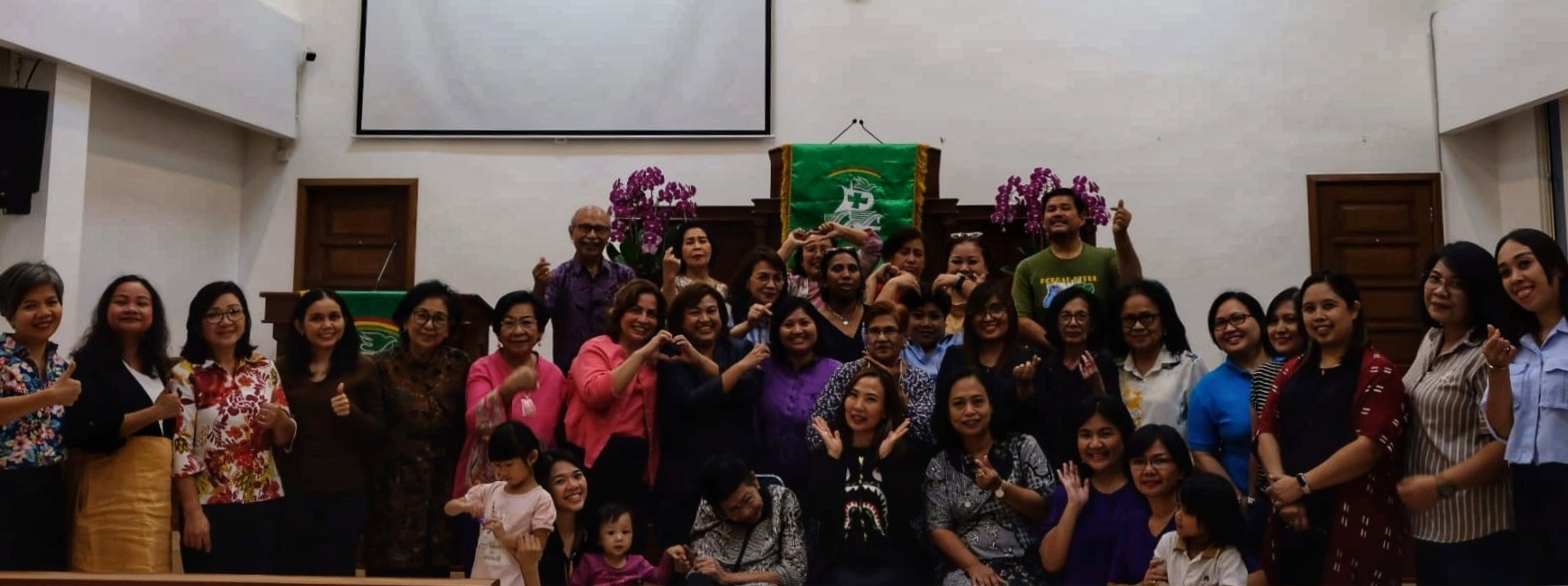 Pembicara sedang mempresentasikan materi di hadapan peserta berbaju merah